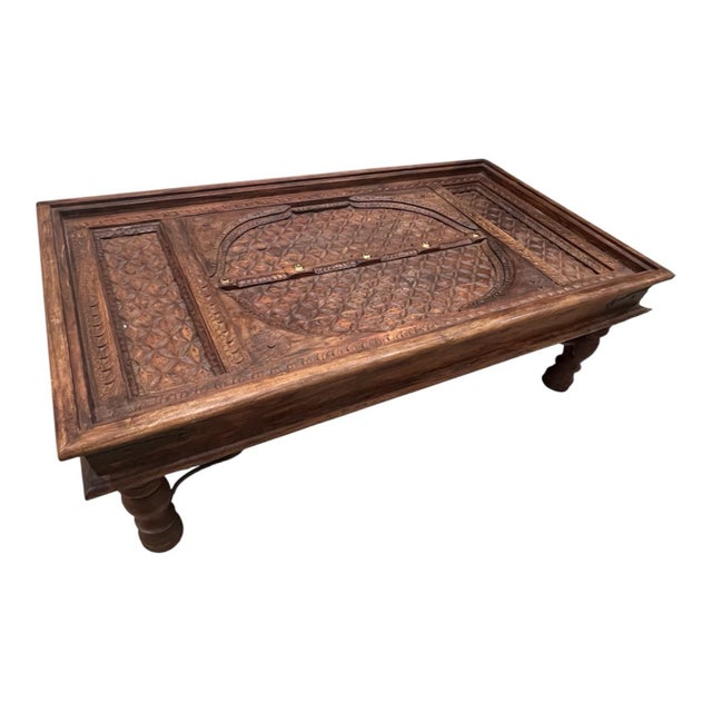 Hand-carved Indian door-panel coffee table featuring deeply carved geometric and floral-style motifs, turned wood legs,...