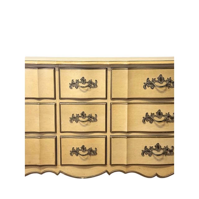 A charming vintage French Provincial triple dresser finished in a warm butter yellow paint, featuring a graceful...