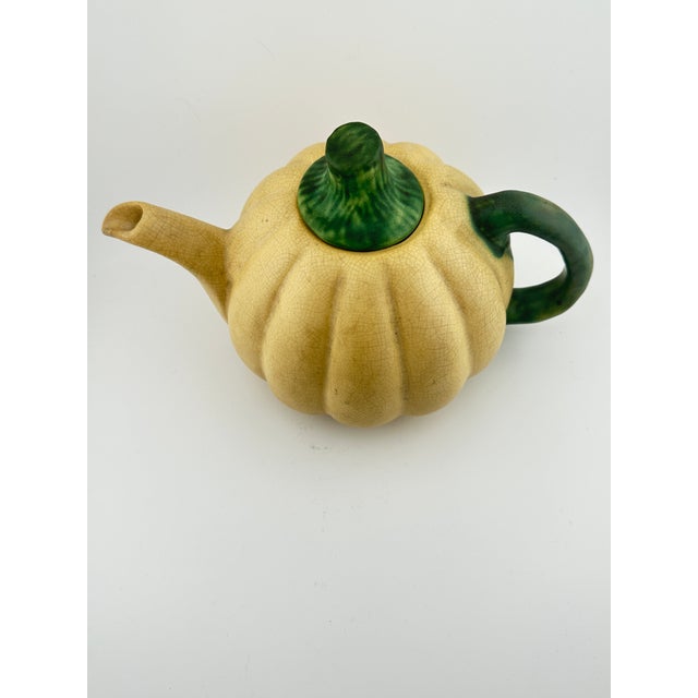 Vintage Weller Squash Teapot featuring a pumpkin shaped body with green handle and stem shaped cover. Part of the paper...