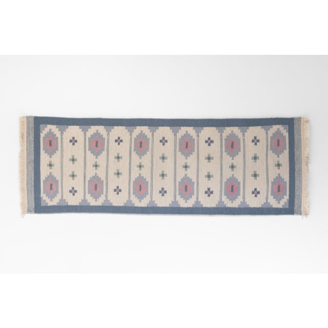 Swedish floor runner with a geometric design in tones of blues, cream and pinks. Sweden circa 1970. All rugs undergo a...