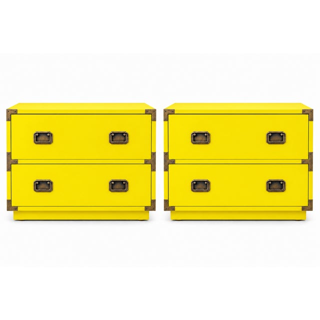 A striking pair of campaign-style nightstands with a vivid yelliow finish and warm brass-tone hardware. Each nightstand...