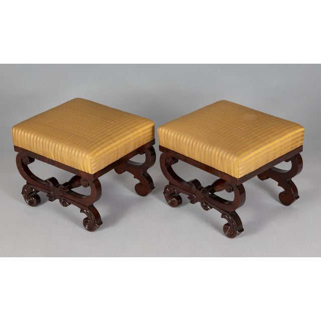 Pair American Classical solid mahogany footstools, each upholstered in a gold striped silk fabric, the scrolled X-frame...