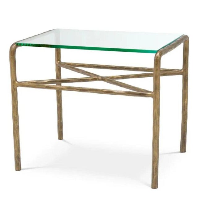 Pair of contemporary side table featuring a clear glass top and a hammered vintage brass finish frame. The rectangular...