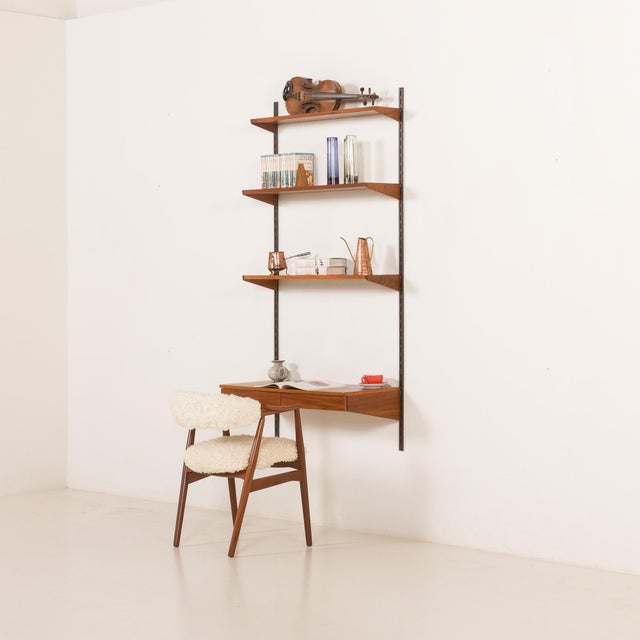 An elegant teak shelving system, designed by kai kristiansen, will create a functional and stylish working space for a...