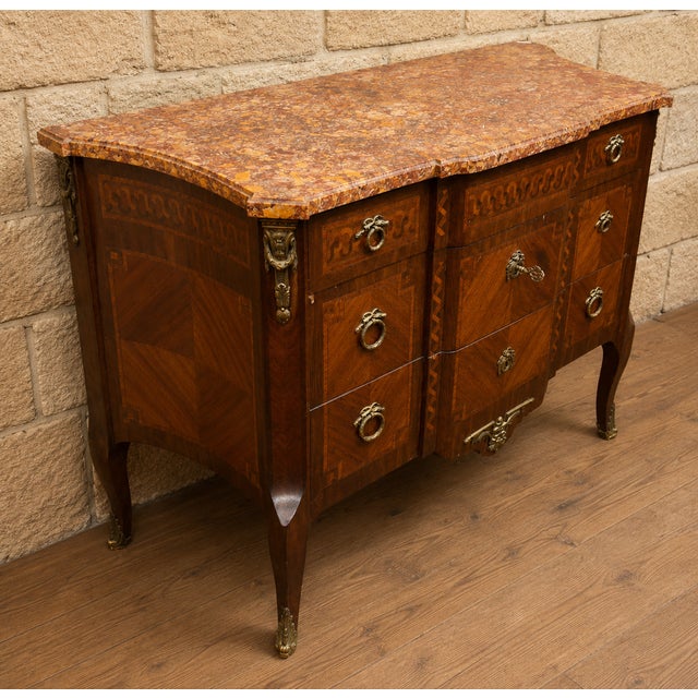 An elegant bombé commode in veneered and inlaid wood, in the Louis XV-Louis XVI Transition style. The front features a...