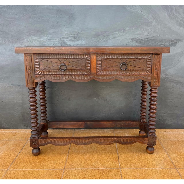 Elegant Spanish console table crafted in solid wood, featuring turned legs and two finely hand-carved drawers with...