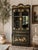Striking Korean vintage chinoiserie display cabinet finished in dramatic black lacquer with intricate gold floral and...