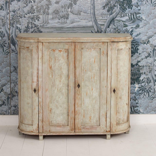 A Swedish buffet in original paint from the Gustavian period. This piece has lovely demilune sides with 3 fixed shelves on...
