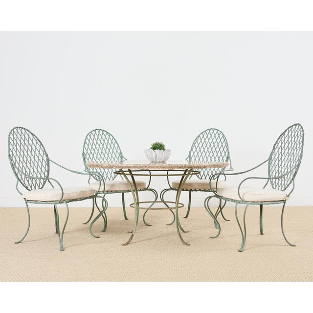 Iconic patio and garden dining suite consisting of four iron armchairs and one 53.5 inch by 28.5 inch high round stone top...