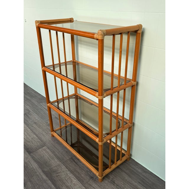 Vintage bookcase with a bamboo frame and smoked glass shelves. Made in Italy in the 1980s. The frame is made of bamboo...
