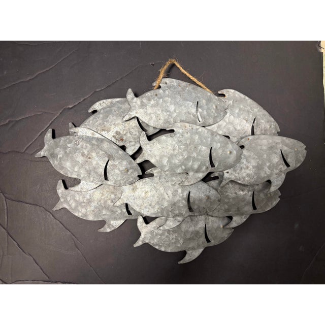 A striking galvanized metal wall sculpture featuring a school of fish in layered relief. Crafted from galvanized steel...