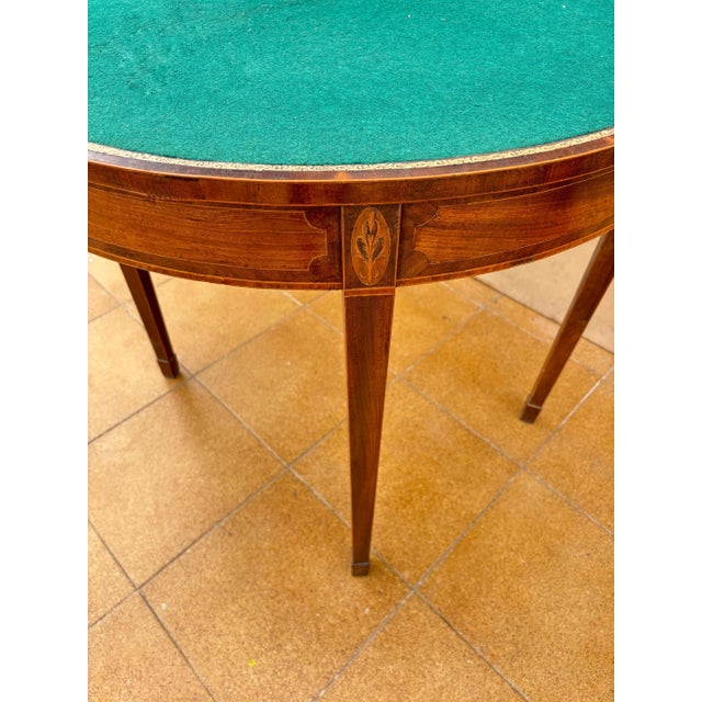 Elegant demi-lune table crafted in finely finished wood, featuring a refined green leather inset top. The curved...