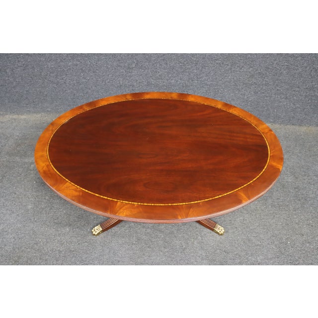 Henkel Harris oval mahogany coffee table featuring a richly figured mahogany top framed by a satinwood-style banded inlay....