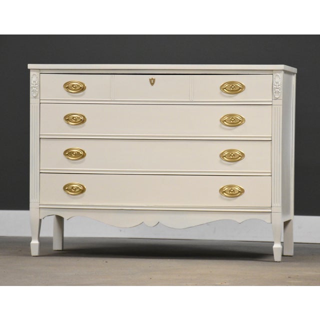 A painted white dresser with four dovetail drawers and gold painted drawer pulls made by Dixie Furniture. Minor...