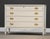 A painted white dresser with four dovetail drawers and gold painted drawer pulls made by Dixie Furniture. Minor...