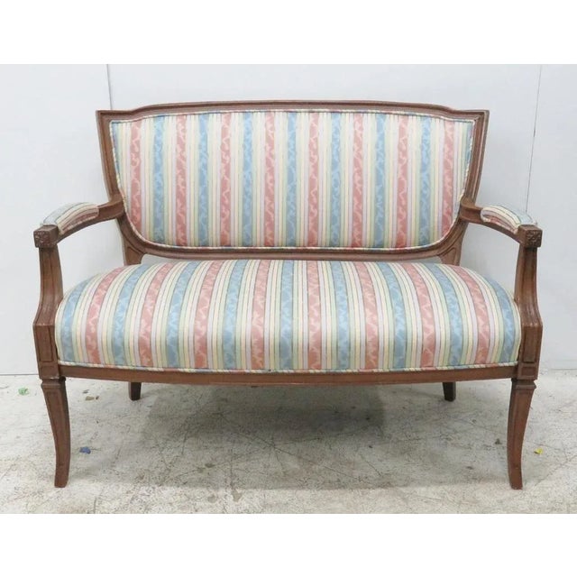 French settee frame is made of cherry with a shieldback design, saber legs, and carved detailed arms. seat height is 17"