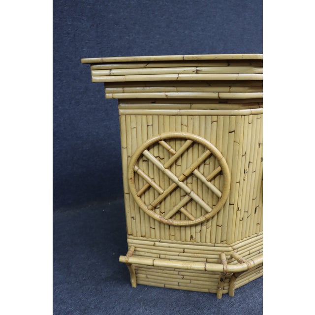 A distinctive mid-century modern split bamboo and rattan dry bar featuring a sculptural angular form with a durable white...