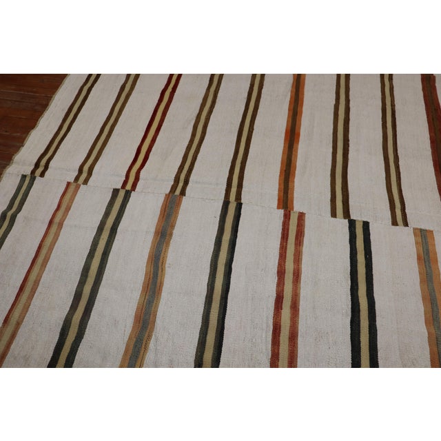 A large square turkish klim with a rustic stripe pattern on an ivory background from the third quarter of the 20th...