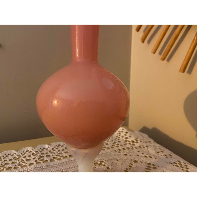 A striking vintage decorative glass vase featuring a rich, opaque rose-pink body, an elegantly elongated trumpet neck and...