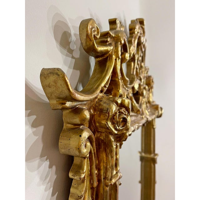A striking vintage (circa 1970s–1980s) gilded Baroque-style wall mirror, featuring an elaborate hand-carved frame with...