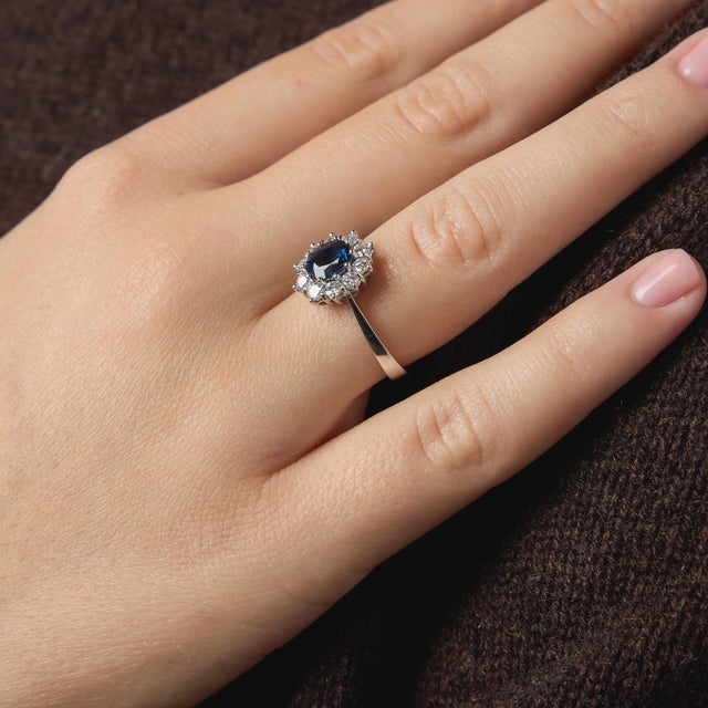 This elegant vintage cluster ring showcases a richly colored cushion cut sapphire, radiating deep, captivating hues that...