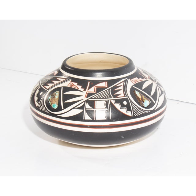 A pottery vessel by Ute Mountain Ute potter Robert Reid. This vase has a hand-painted red and black design against a white...