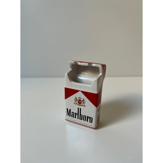 Vintage ceramic ashtray molded to replicate a Marlboro cigarette pack with dimensional red and white graphics. Features...