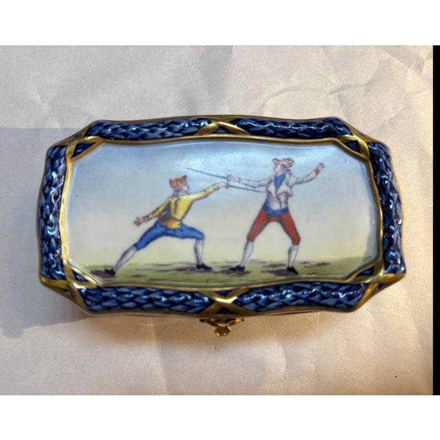 A small French Sevres porcelain hand painted box with hinged lid. The vibrant color with gilt accents depicting 18th...