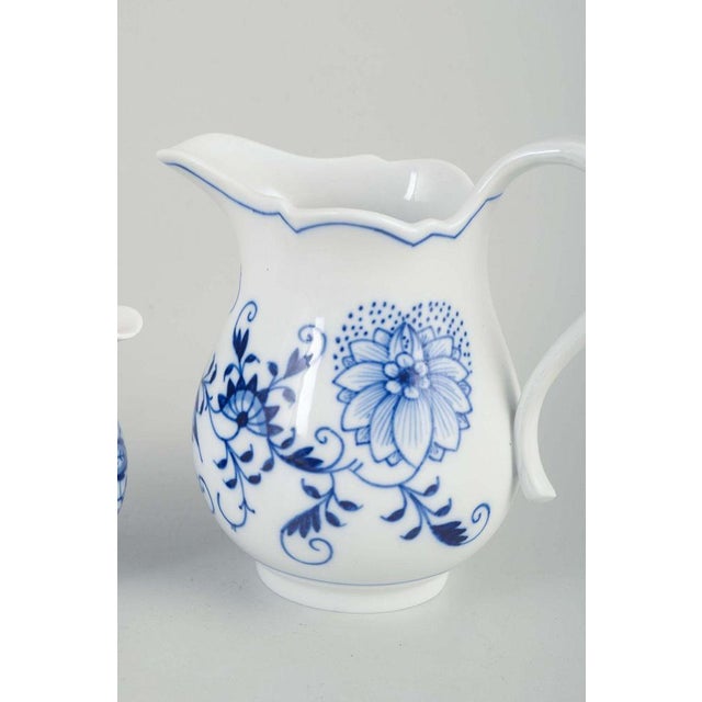 Meissen blue onion Two creamers, early 20th century. Porcelain creamers with white glaze and hand-painted blue floral...