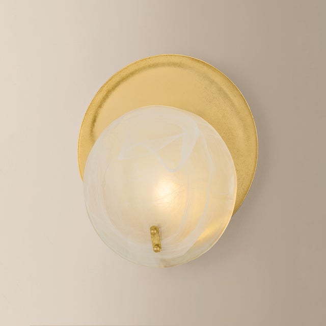 Shanette elevates a simple, rounded sconce form with statement materials. The soft white swirls of the Piastra glass shade...