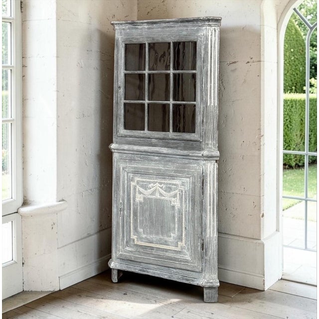 An exceptional 18th century French Neoclassical painted corner vitrine, crafted with the refined architectural form and...