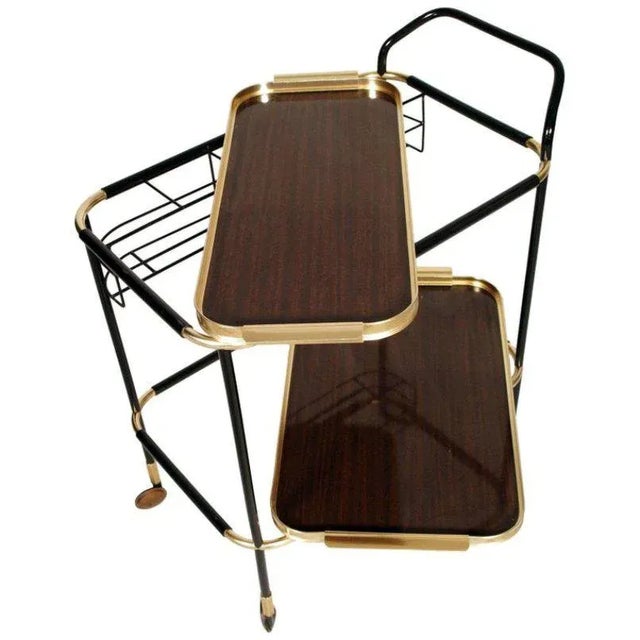 - 1960s bar trolley - 2 removable Formica trays - Gold-colored metal detailing covered in black resin - Black-lacquered...