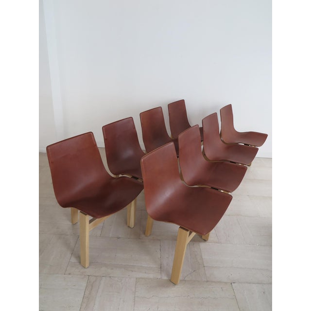 Set of eight 3T model chairs designed by Angelo Mangiarotti in 1978, featuring an oak frame and leather seat. Produced by...