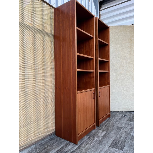 A pair of Vintage Single-Column Danish Teak Bookcases with Cabinet Storage. Circa 1970s Features a mid-century modern...