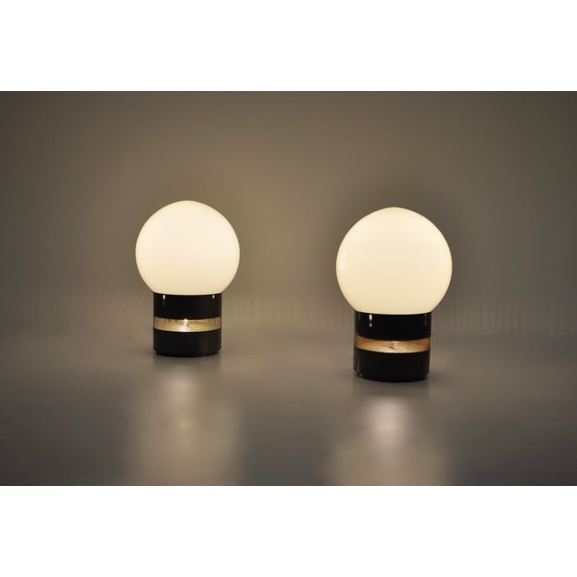 Pair of metal lamps with glass ball. Oracolo model by Gae Aulenti. Wear due to time and the age of the lamp. This piece is...