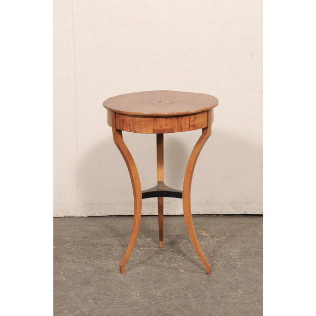An Italian round-shaped side table, with decorative veneers and inlay, from the 19th century. This antique table from...