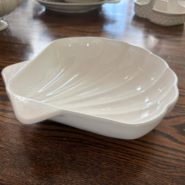 Elegant white glazed ceramic serving bowl designed in the shape of an oversized scallop shell. Features softly sculpted...