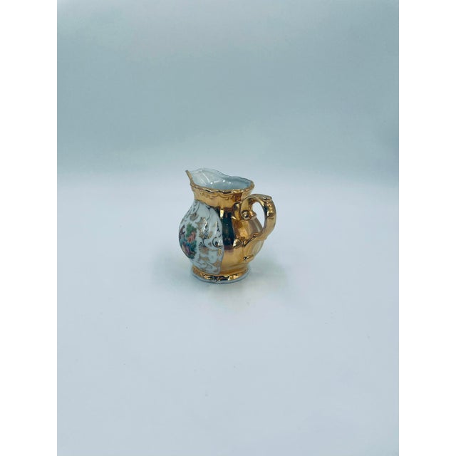 A milk jug of Italian origin, crafted from high-quality porcelain. The jug features a delicately curved handle, rich...