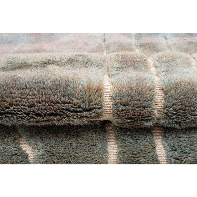 Abstract hand-knotted wool rug in serene Sky Blue, Dove Grey, and Sage Green with subtle Ivory line accents. Its soft...