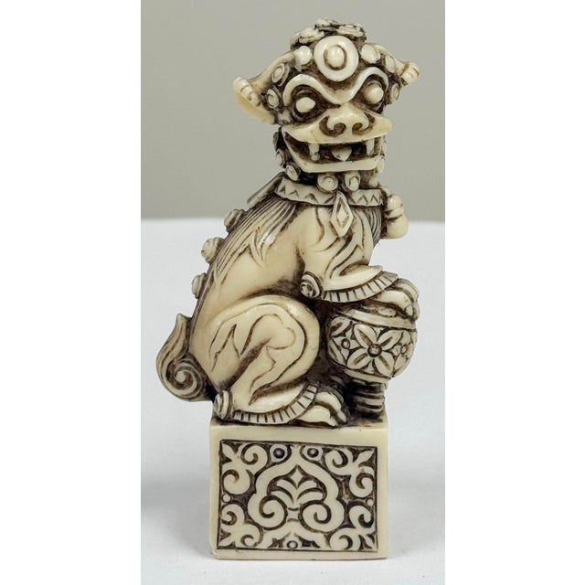 Vintage detailed ivory resin foo dog figure. Seated with ornate ball on decorated block. Marked to underside. Made in...