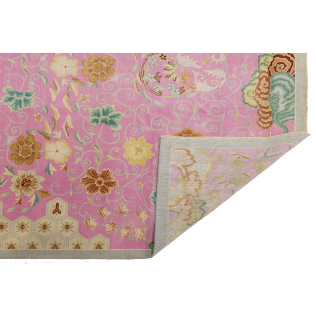 This beautiful hand-knotted wool rug features a stunning pink color palette, complemented by delicate brown and...