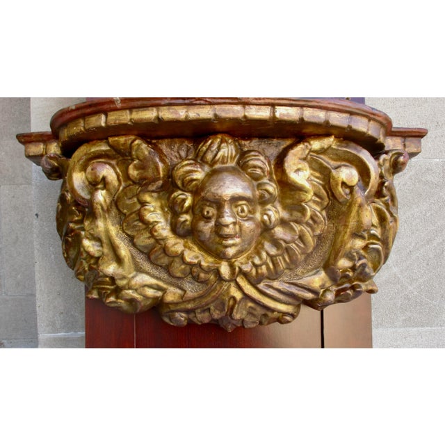 Gilt wood carved Italian Country bracket. Classical baroque winged putti supporting a demilune shelf overhead. Faux-...