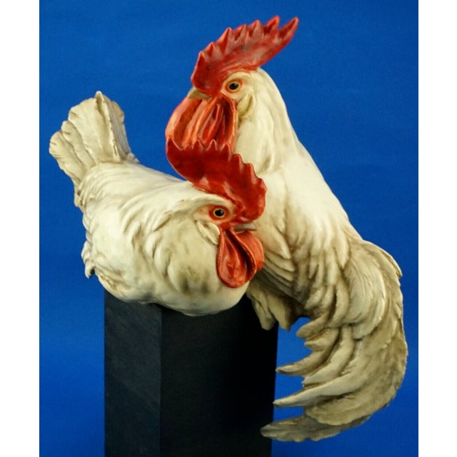 A stunning, large glazed stoneware sculpture depicting a pair of roosters perched on a block of black wood, created by the...
