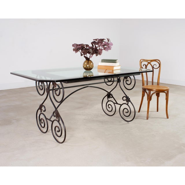 Whimsical 20th century Italian wrought iron patio and garden dining table with a glass top. The table features an iron...