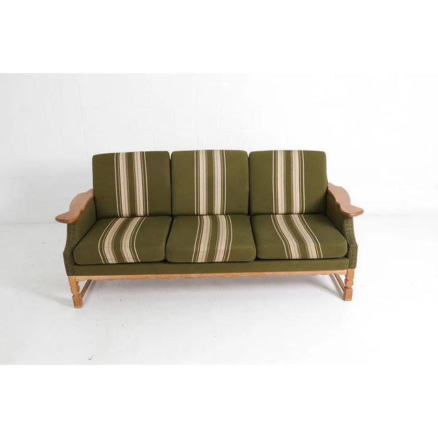 A solid and well-made mid-century (circa 1960's) paddle arm type sofa. The sofa has a solid oak wood carved/figured frame...