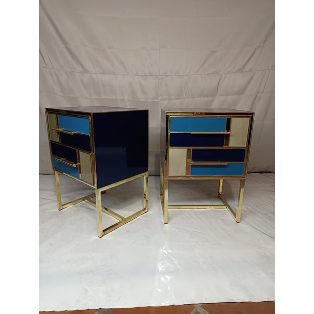 The bedside tables, with their blue and gold glass surfaces, convey a sense of freshness and elegance. Refined brass...