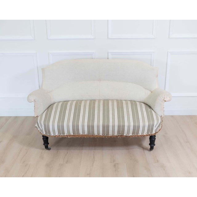 A beautiful antique French arch top sofa featuring an elegant curved back and refined carved detailing characteristic of...