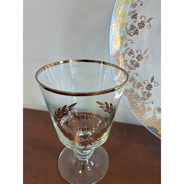 A charming vintage glassware set featuring a decorative “Happy Anniversary” plate paired with a coordinating goblet, both...