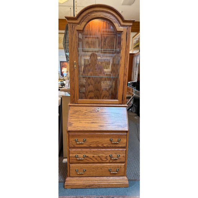 Design Plus Gallery presents a Bonnet Top Secretary from Jasper Cabinet. The secretary has a golden tan tone with their...