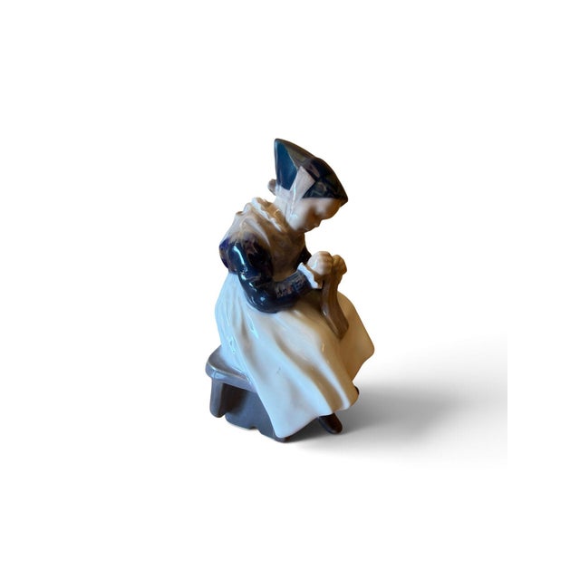 Elegant hand-painted porcelain figurine depicting a young girl in traditional Danish dress. The figure is beautifully...